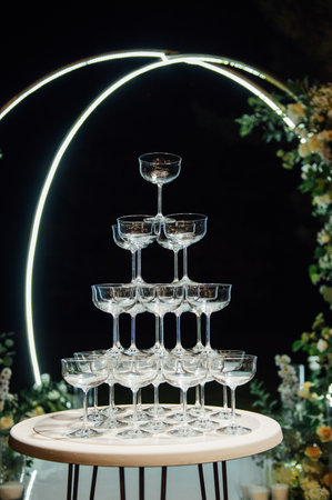 A large pyramid of champagne glasses at an evening ceremony near the arch.の写真素材