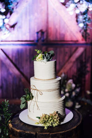Beautiful wedding arch with wooden decorative door and flowers. A large wedding cake.の写真素材