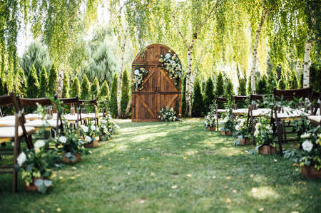 A beautiful area for an outdoor wedding ceremony. Arch Decorated with a large wooden door with many flowers.の写真素材