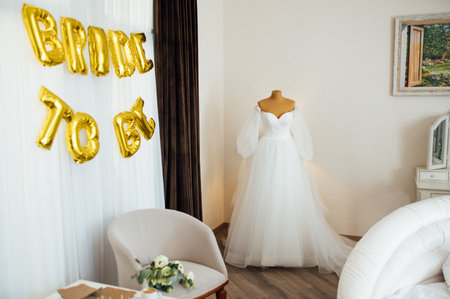 The brides dress hangs on the window. A gentle bouquet of the bride and womens shoes stand on the windowsillの写真素材
