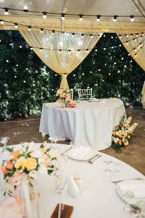 Evening decoration of a wedding party. Tables for guests with a garland and lampsの写真素材