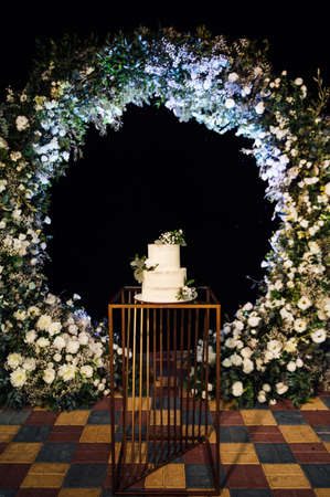 Beautiful wedding cake with flowers and a large wedding arch.の写真素材