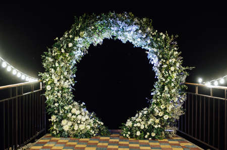 Round wedding arch decorated with fresh flowers. Evening ceremonyの写真素材