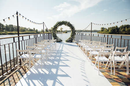 Circle wedding arch decorated with white flowers and greenery outdoors.の写真素材