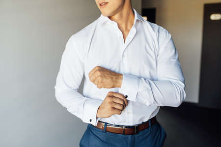 Young businessman in a blue suit straightens a cufflink on a white shirtの写真素材