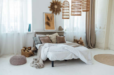 Comfortable bed with warm knitted plaid in stylish room interiorの写真素材