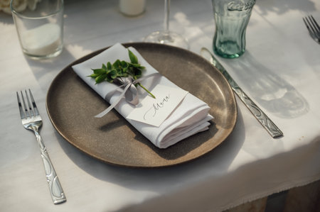 The festive table is served with plates with napkins and name cards, glasses and cutlery.