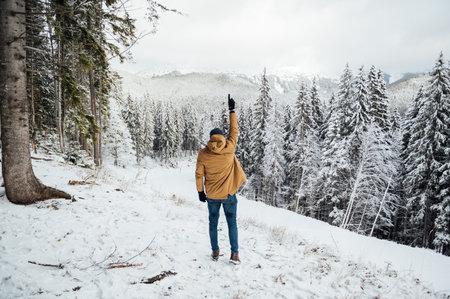 A handsome guy stands with his back and enjoys the view of the winter mountainsの写真素材
