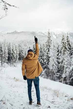 A handsome guy stands with his back and enjoys the view of the winter mountainsの写真素材