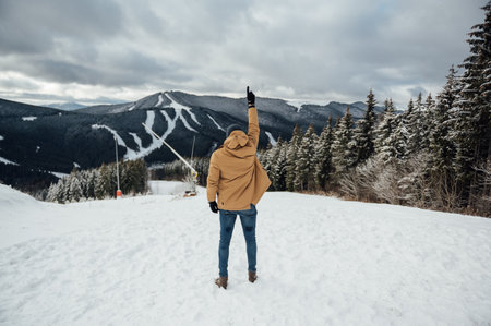 A handsome guy stands with his back and enjoys the view of the winter mountainsの写真素材