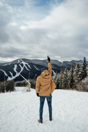 A handsome guy stands with his back and enjoys the view of the winter mountainsの写真素材