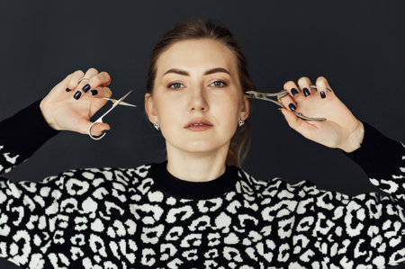 The nail master holds scissors and other tools in his hands. Beautiful blonde girlの写真素材