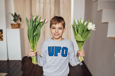The boy smiles fervently with a bouquet of flowersの写真素材