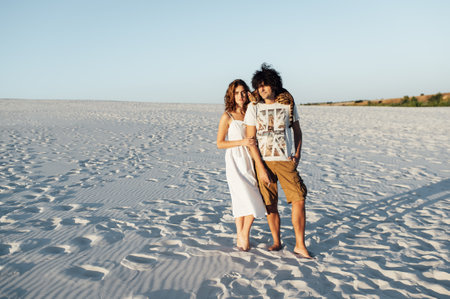 Cheerful young couple having fun on the beach with their bengal catの写真素材