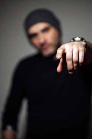Serious dramatic man looking away while standing against black studio backgroundの写真素材