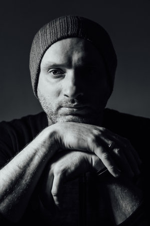 Serious dramatic man looking away while standing against black studio backgroundの写真素材