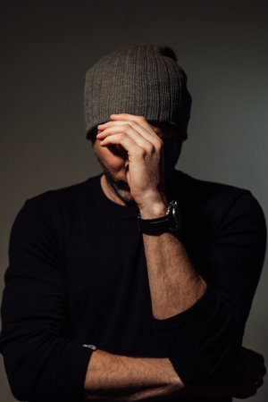 Pretty dramatic man looking away while standing against black studio backgroundの写真素材
