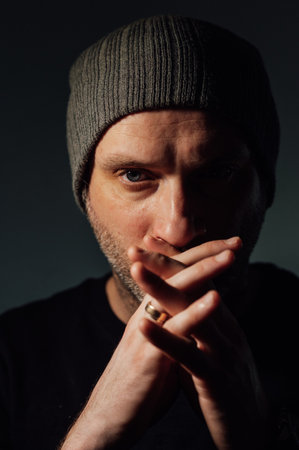 Serious dramatic man looking away while standing against black studio background