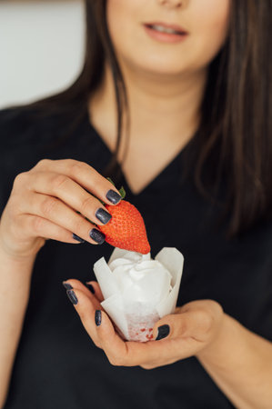 Close up portrait of pretty young brunette woman with bright make up eating tasty cake with berries and creamの写真素材