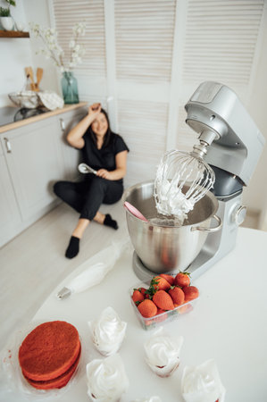 Woman cook sits on the floor against the background of a blender.の写真素材
