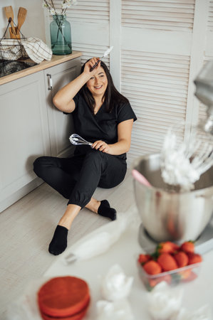 Woman cook sits on the floor against the background of a blender.の写真素材