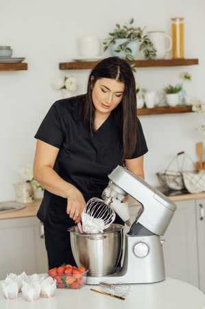 The girl cook puts the cream from the mixer into the mold for decorating cakesの写真素材