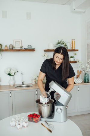 The girl cook puts the cream from the mixer into the mold for decorating cakesの写真素材
