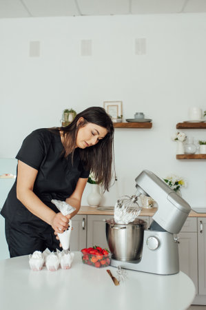 The girl cook puts the cream from the mixer into the mold for decorating cakesの写真素材