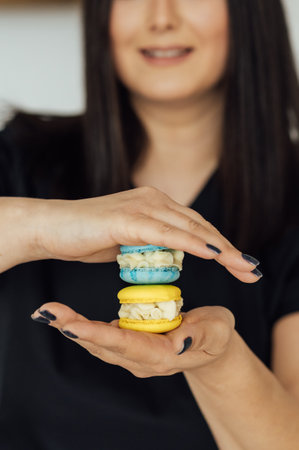 The confectioner is holding two yellow and blue French macarons in her hand. Ukrainian flag colorsの写真素材