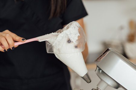 The girl cook puts the cream from the mixer into the mold for decorating cakes