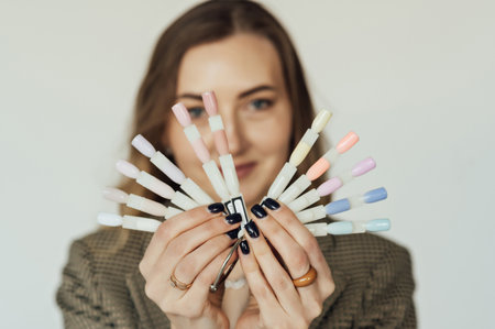 Professional woman master of manicure posing with samples of nails. The nail technician holds the sample palette.の写真素材