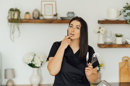 Woman cook tastes the cream for cakes whipped in a mixerの写真素材