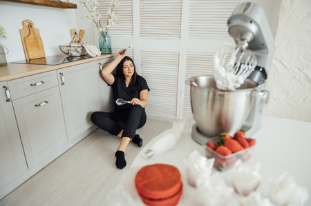 Woman cook sits on the floor against the background of a blender.の写真素材