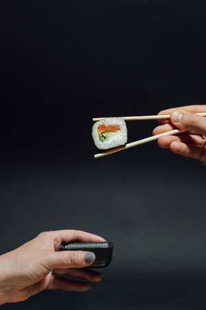 Girls hands hold sushi rolls with bamboo sticks. Japanese traditional foodの写真素材