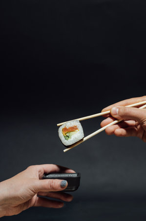 Girls hands hold sushi rolls with bamboo sticks. Japanese traditional foodの写真素材