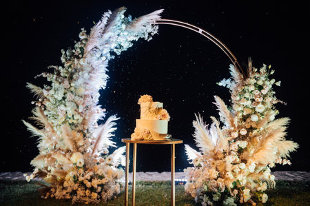 Beautiful wedding cake with flowers and a large wedding arch.の写真素材