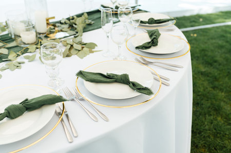Open -air wedding banquet. The table is decorated with white plates and premium glasses for wineの写真素材