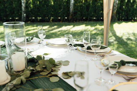Open -air wedding banquet. The table is decorated with white plates and premium glasses for wine