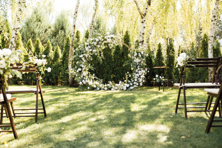 Circle wedding arch decorated with white flowers and greenery outdoors.の写真素材