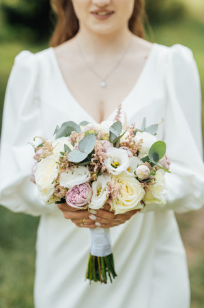 Wedding Flowers Roses Bouquet in Bride Hands with White Dress on Backgroundの写真素材