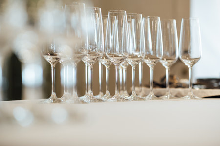 Row of empty champagne glasses on a table outdoors with sun reflection. Selective focus. Celebration conceptの写真素材