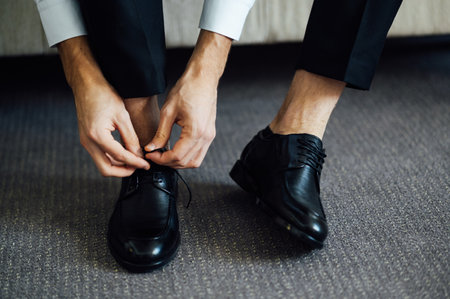 Man ties his black shoes. Close-up viewの写真素材