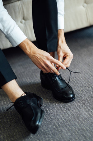 Man ties his black shoes. Close-up viewの写真素材