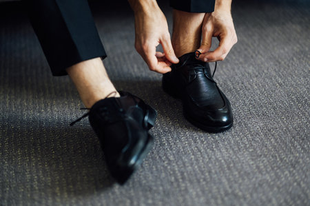 Man ties his black shoes. Close-up viewの写真素材