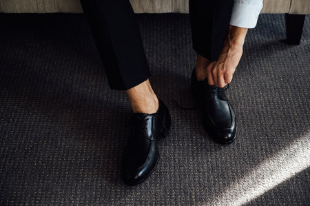 Man ties his black shoes. Close-up viewの写真素材
