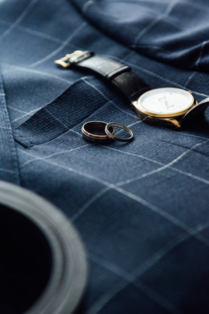 Grooms wedding details. Watch, rings and belt placed on a checkered jacketの写真素材