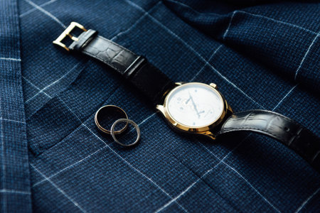 Grooms wedding details. Watch, rings and belt placed on a checkered jacketの写真素材
