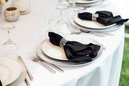Open -air wedding banquet. The table is decorated with white plates and premium glasses for wine