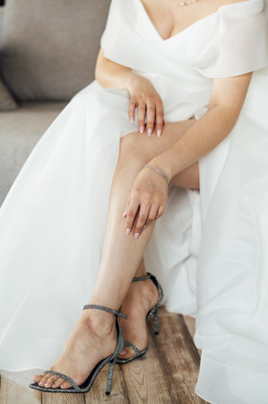 The bride in a wedding dress puts sandals on her feet. Wedding bride shoesの写真素材