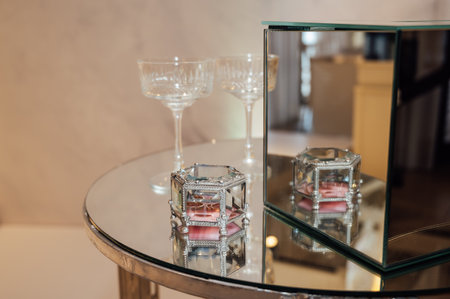 Two wedding glasses stand on a stand against the backdrop of the ceremony arch.